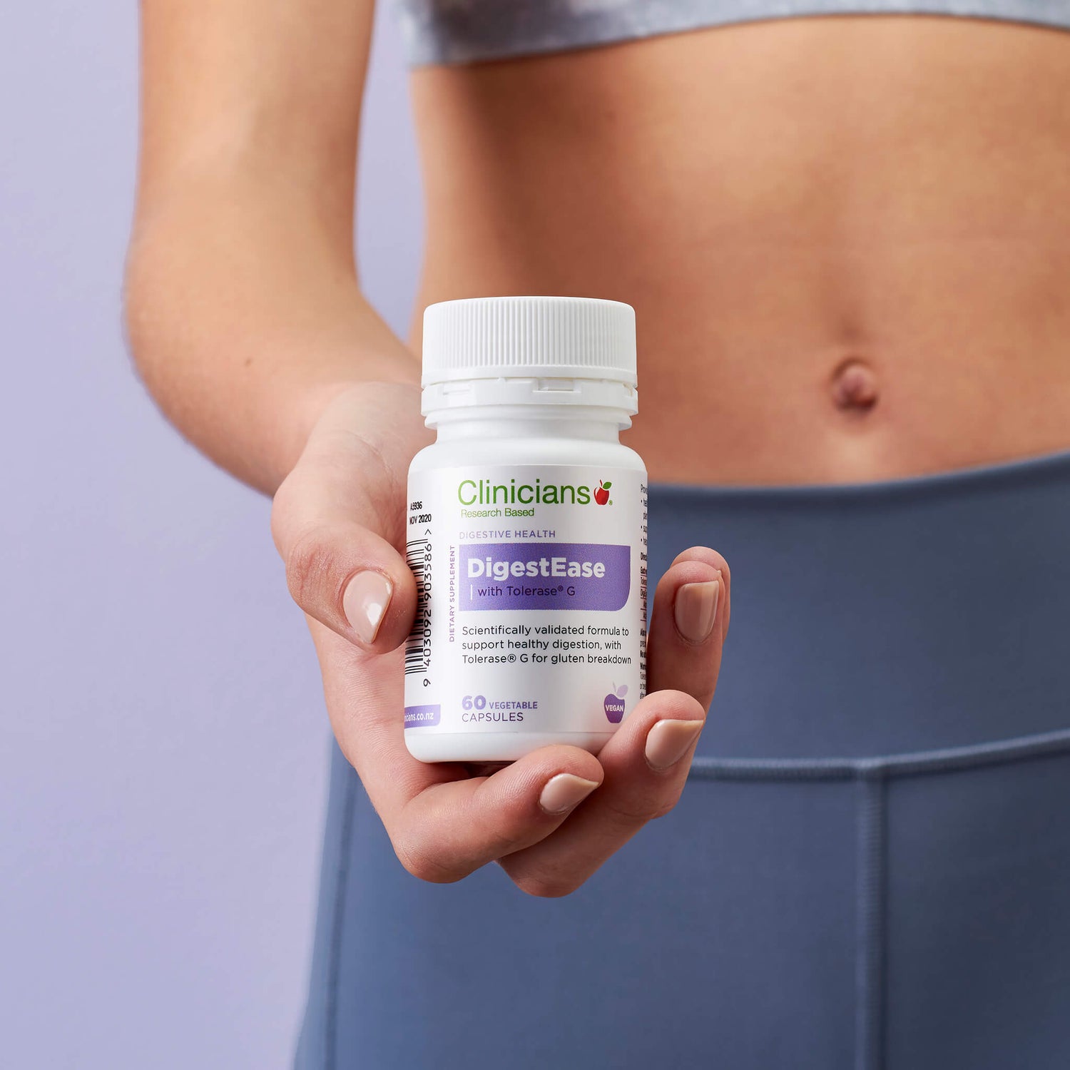 Woman holding product packaging in front of bare stomach