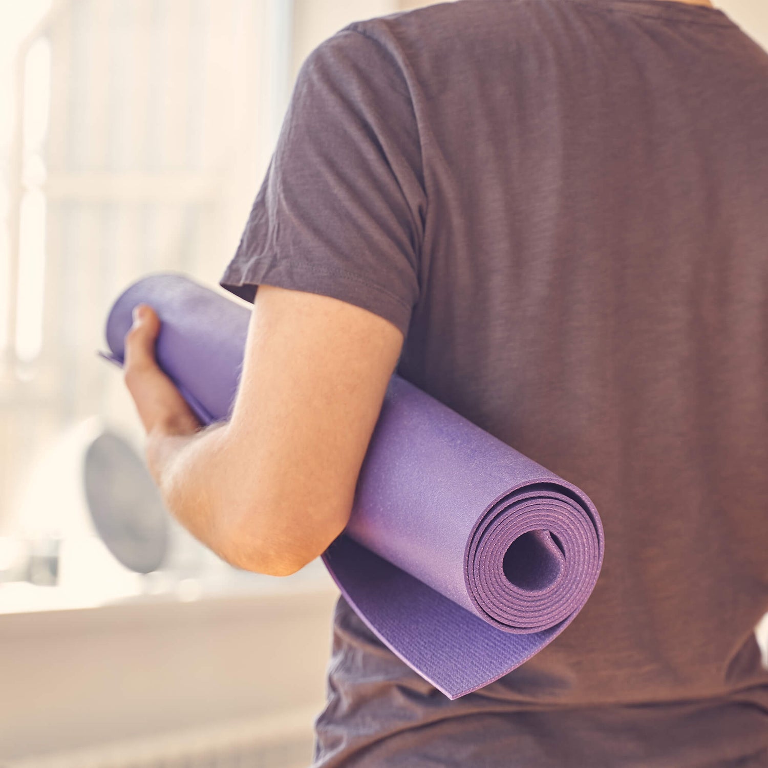 Man carrying yoga mat under arm